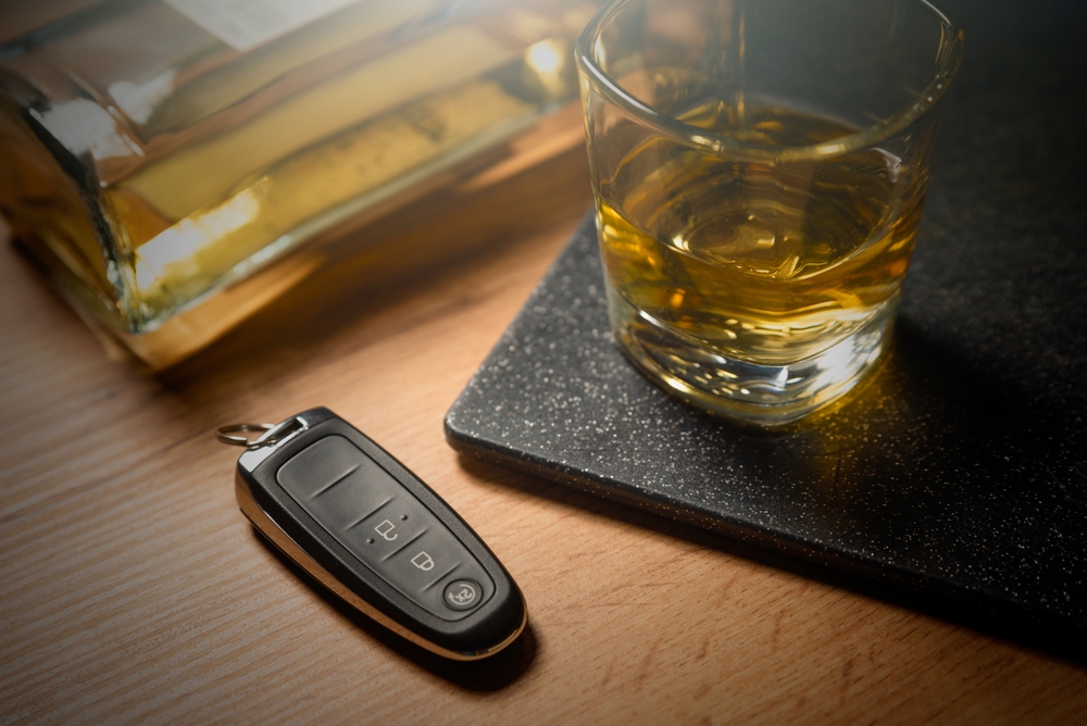Car key next to a glass of whiskey representing Nebraska DUI charges and alcohol impairment concerns