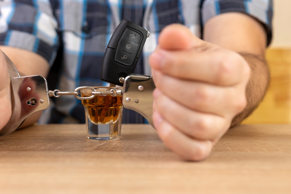 Handcuffed individual with car keys and alcohol symbolizing DUI arrest consequences in Nebraska