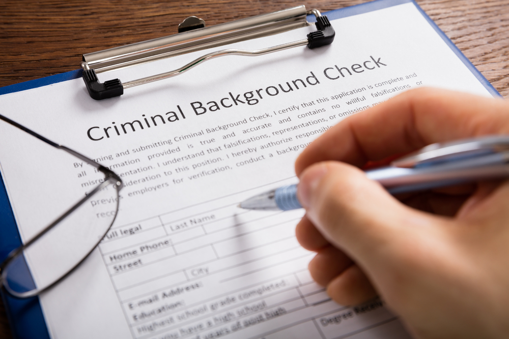Close-up of person's hand filling out a criminal background check form