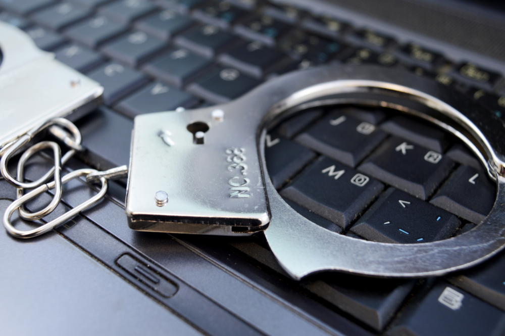 Stylized image of cybercrime, showing handcuffs on a laptop keyboard